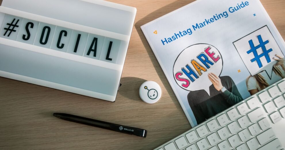 A desktop setup with social media marketing essentials including a keyboard, lightbox, and guide.