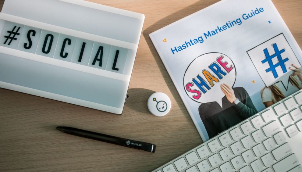 A desktop setup with social media marketing essentials including a keyboard, lightbox, and guide.