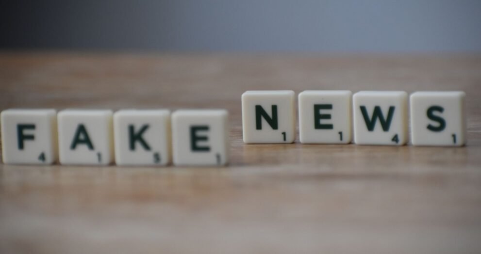 Scrabble tiles spelling 'Fake News' on a wooden surface highlighting misinformation.