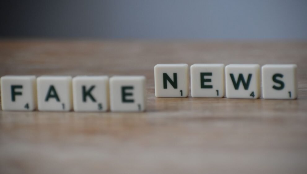 Scrabble tiles spelling 'Fake News' on a wooden surface highlighting misinformation.
